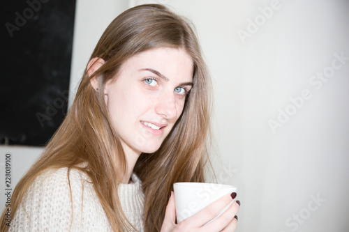 cheerful young woman drink tea coffee in white mug at home lifestyle