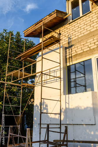 Insulation of the house with styrofoam. Scaffold on building © ihorbondarenko