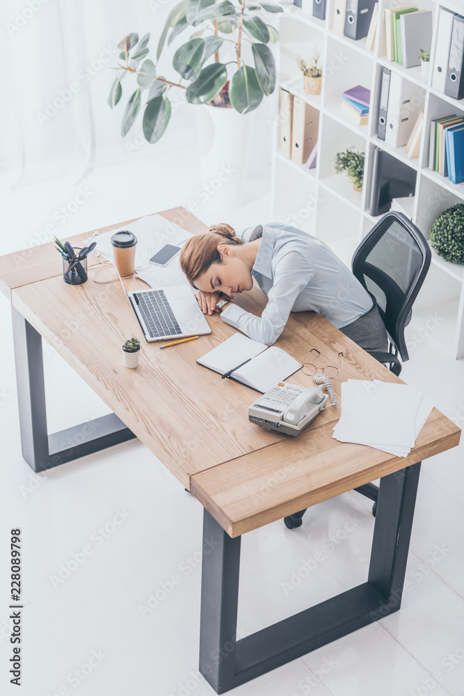 high angle view of overworked adult businesswoman sleeping at workplace high angle view of overworked adult businesswoman sleeping at workplace