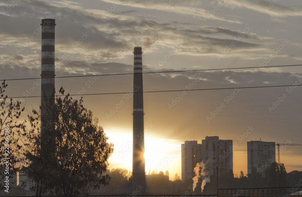TPP thermal power plant on a sunrise. Refinery with smokestacks. Smoke from factory pollutes the environment. High red and white tower of CHPP. TPP produce steam for electric power. Pollution, climate