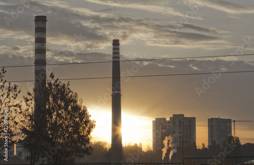 TPP thermal power plant on a sunrise. Refinery with smokestacks. Smoke from factory pollutes the environment. High red and white tower of CHPP. TPP produce steam for electric power. Pollution  climate