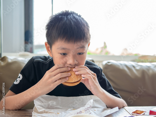 Εκτύπωση καμβά A sad moody boy eating hamburger in the hamburger shop