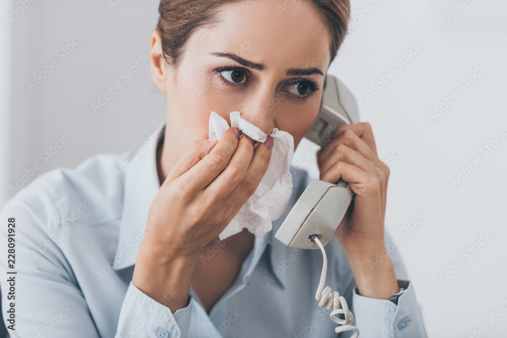 close-up portrait of sick businesswoman with runny nose talking by wired phone close-up portrait of sick businesswoman with runny nose talking by wired phone