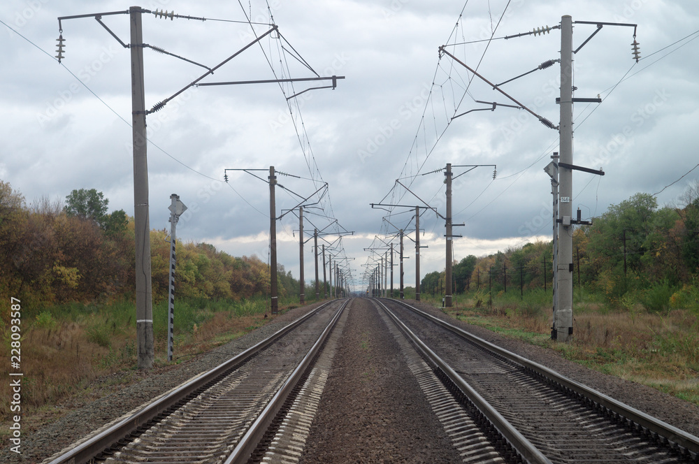 Autumn railway lines stretching beyond the horizon. Overcast October industrial landscape under heavy leaden sky