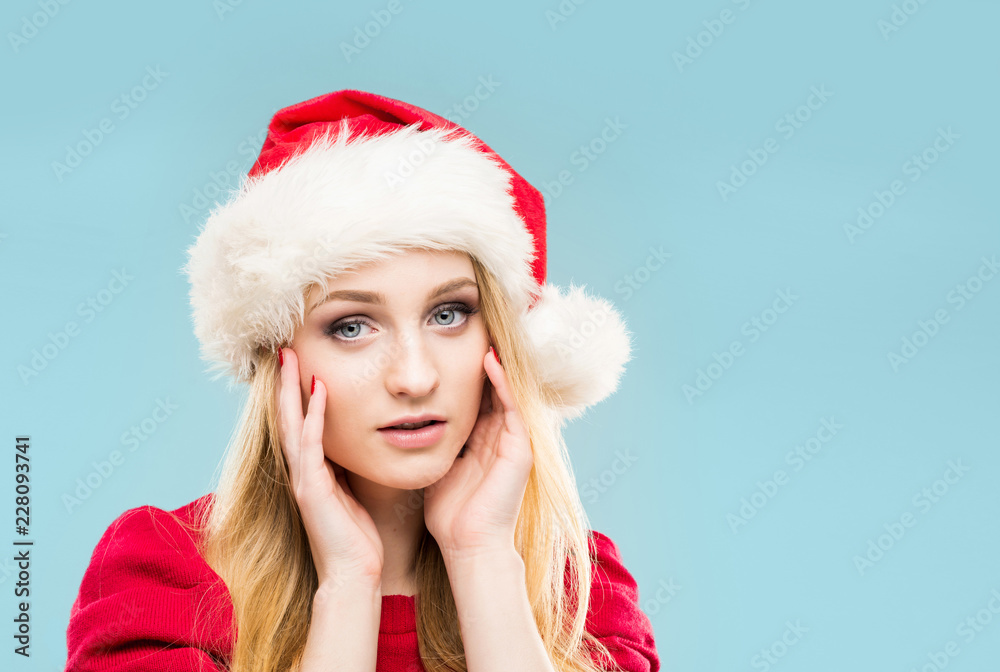 Beautiful, young and pretty girl in Christmas hat over background with snow. Beautiful, young and pretty girl in Christmas hat over background with snow.