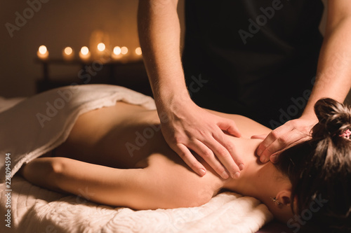 Close up Male manual worker doing spa massage to a young girl in a dark room