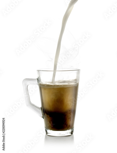 Un chorro de leche cayendo sobre una taza de cristal rellena de té