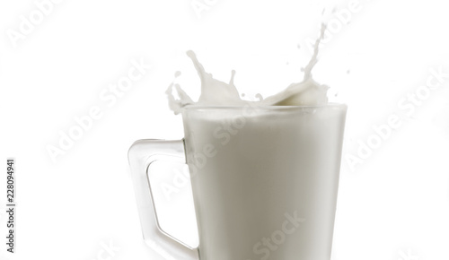 Detalle de un vaso de cristal con un salpicón de leche sobre un fondo blanco 2