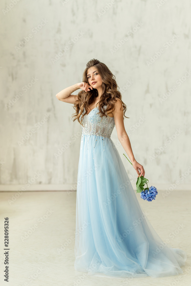Beautiful model in a blue dress whith flower at the white background Beautiful model in a blue dress whith flower at the white background