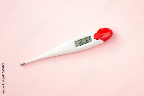 White digital clinical thermometer on pink background shows normal temperature