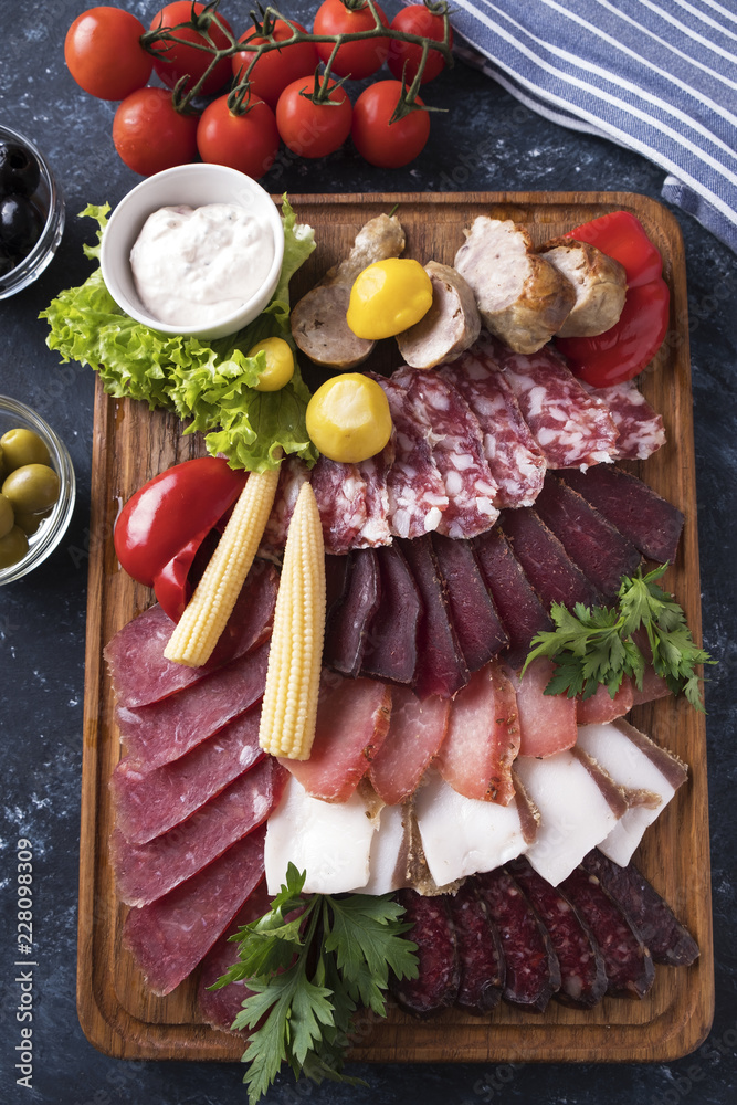 Different sausages with pickled vegetables on wooden board. Closeup. Top view Different sausages with pickled vegetables on wooden board. Closeup. Top view