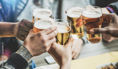 Fotografiet Group of friends cheering with beers in pub restaurant