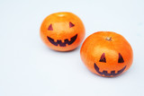Funny orange mandarins or tangerines pumpkin painted in the form of icons of Halloween on the light backround