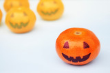 Funny orange mandarins or tangerines pumpkin painted in the form of icons of Halloween on the light backround