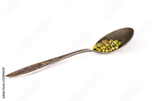 Lot of whole edible dry green mung beans in a spoon isolated on white background