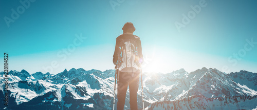 Hiker standing against sun in winter mountains