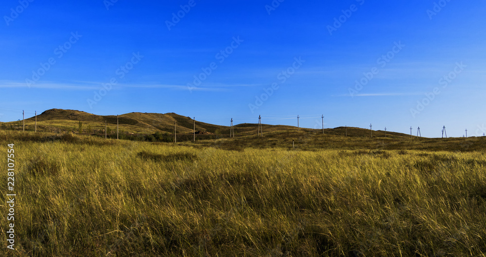 Autumn steppe landscape. Landscape in Kazakhstan. Kazakh steppe. Power line. Blue sky. Yellow grass. Panorama Autumn steppe landscape. Landscape in Kazakhstan. Kazakh steppe. Power line. Blue sky. Yellow grass. Panorama