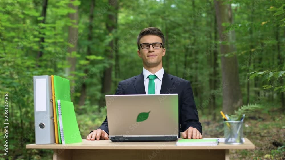 Businessman deeply breathing fresh air in eco-friendly office, working on laptop Businessman deeply breathing fresh air in eco-friendly office, working on laptop