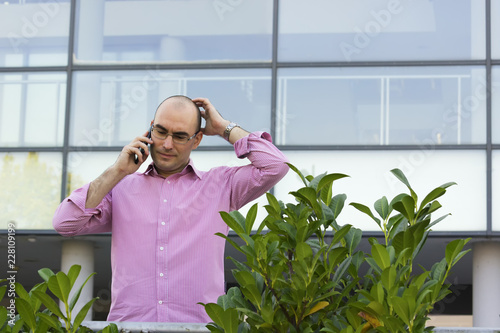 Worried businessman talk on mobile in front of office building