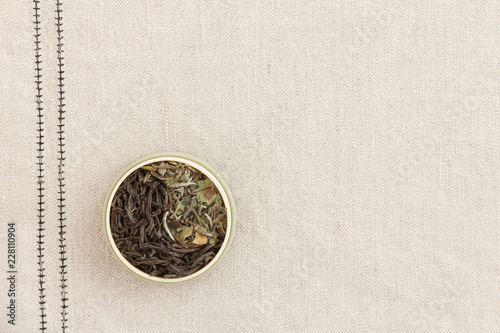 Leaves of black and white tea in a round form on a fabric laid out as a sign of yin and yang