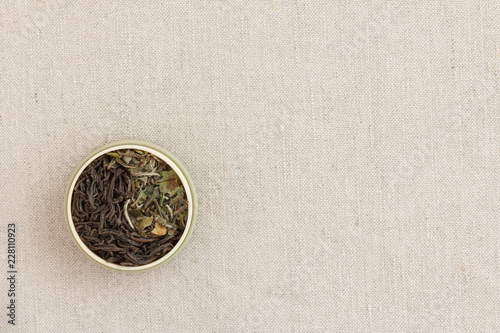 Leaves of black and white tea in a round form on a fabric laid out as a sign of yin and yang