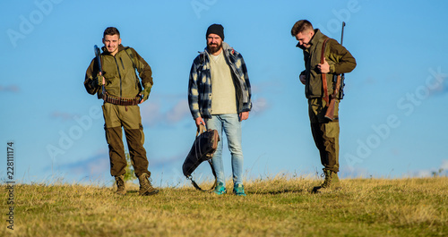 Men carry hunting rifles. Hunters with guns walk sunny fall day. Hunting as hobby and leisure. Brutal hobby. Group men hunters or gamekeepers nature background blue sky. Guys gathered for hunting