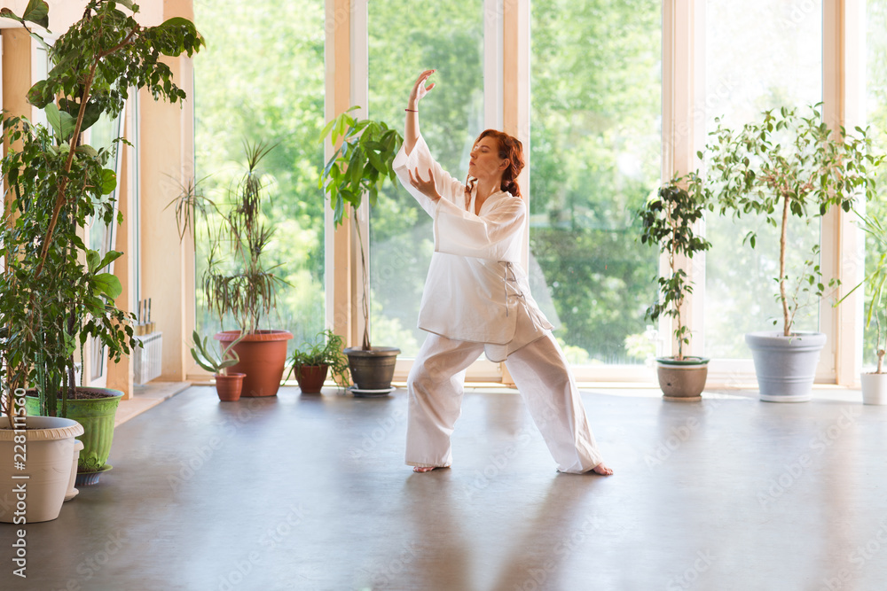 Young Woman praticing tai chi chuan in the home. Chinese management skill Qi's energy. - obrazy, fototapety, plakaty 