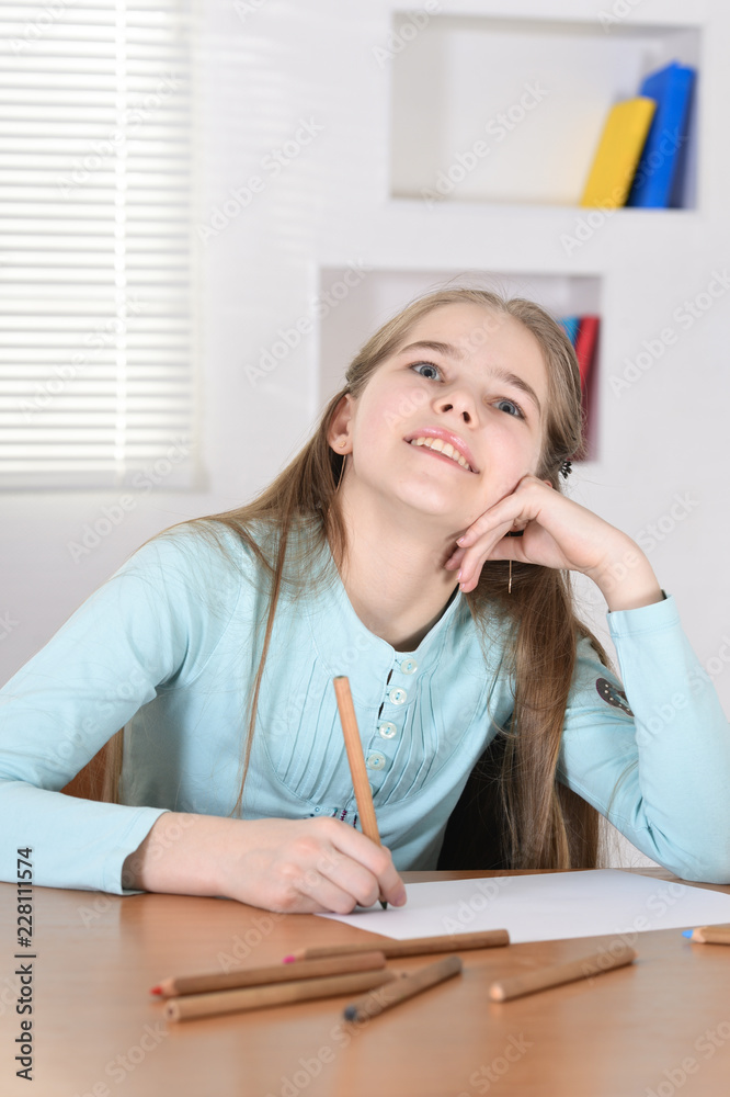 Portrait of cute schoolgirl sitting at table and drawing Portrait of cute schoolgirl sitting at table and drawing