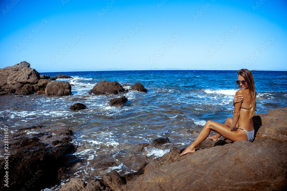 sexy young girl in a bikini on a rocky beach