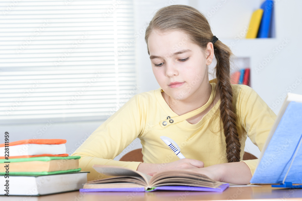 Cute schoolgirl sitting at table and studying Cute schoolgirl sitting at table and studying