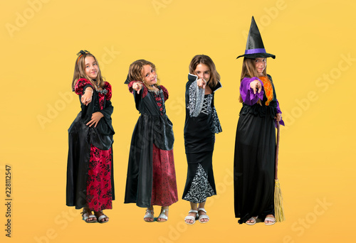 Set of Little girl dressed as a vampire for halloween holidays points finger at you on orange background