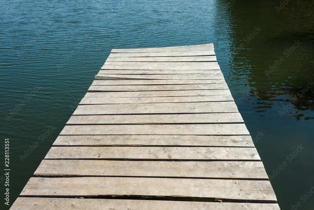 Obraz premium Fragment of an old wooden pier on the background of water