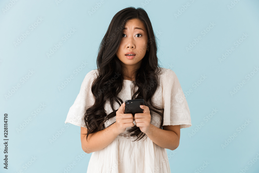Emotional asian beautiful woman isolated over blue background using mobile phone. Emotional asian beautiful woman isolated over blue background using mobile phone.