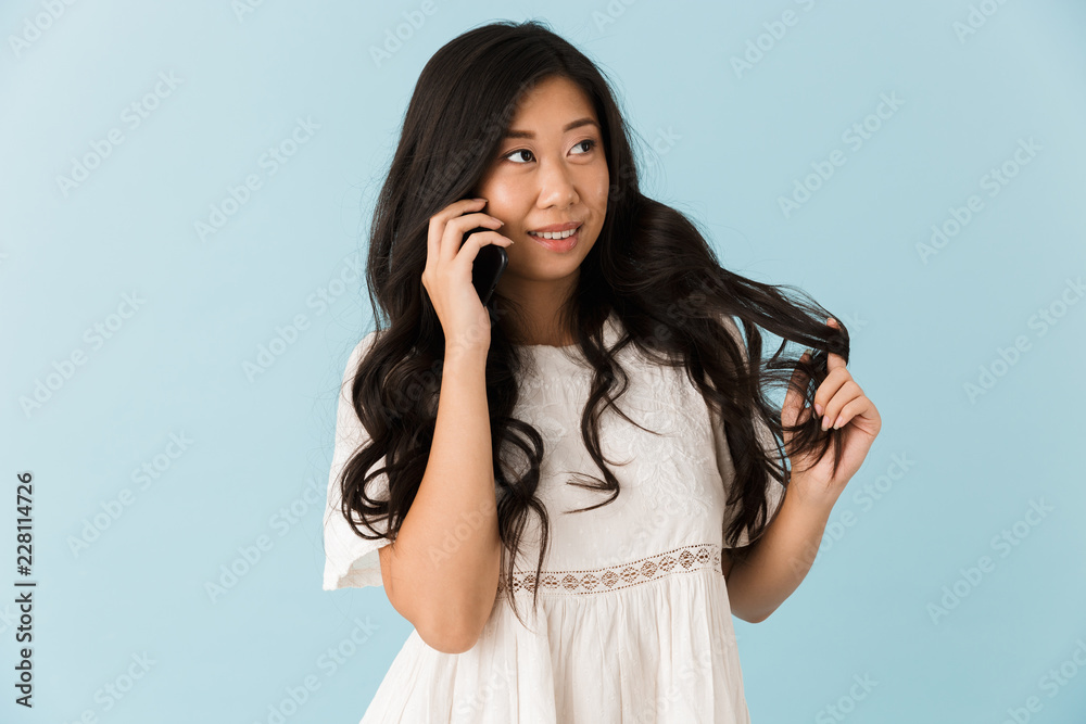 Asian beautiful woman isolated over blue background talking by mobile phone. Asian beautiful woman isolated over blue background talking by mobile phone.