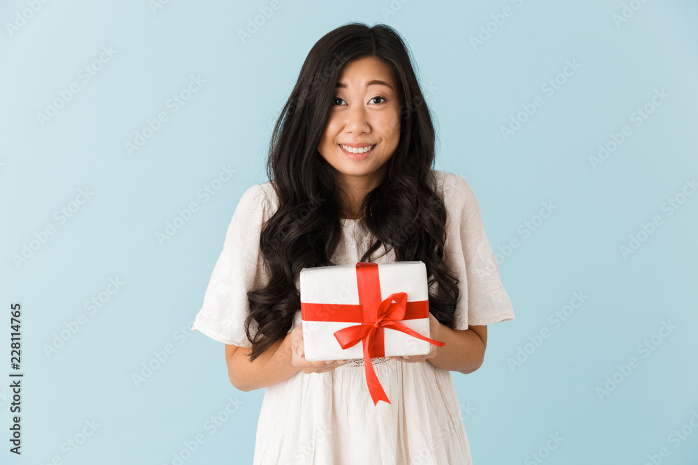 Beautiful woman isolated over blue background holding gift present box. Beautiful woman isolated over blue background holding gift present box.