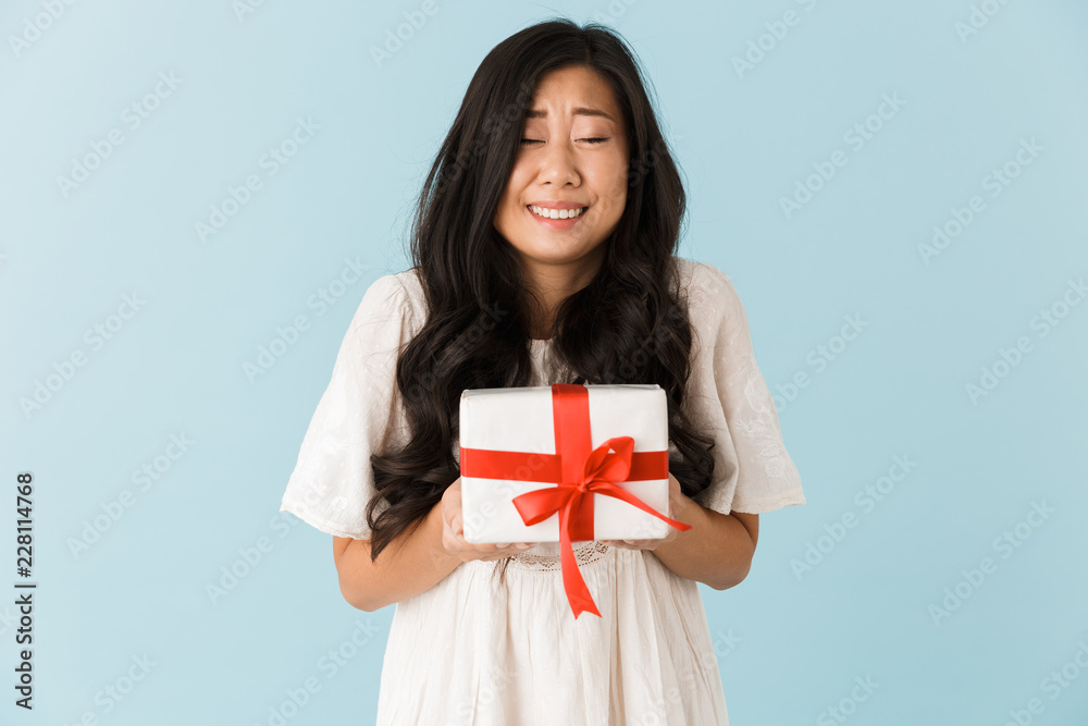 Beautiful woman isolated over blue background holding gift present box. Beautiful woman isolated over blue background holding gift present box.