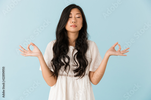 Beautiful woman isolated over blue background meditate.