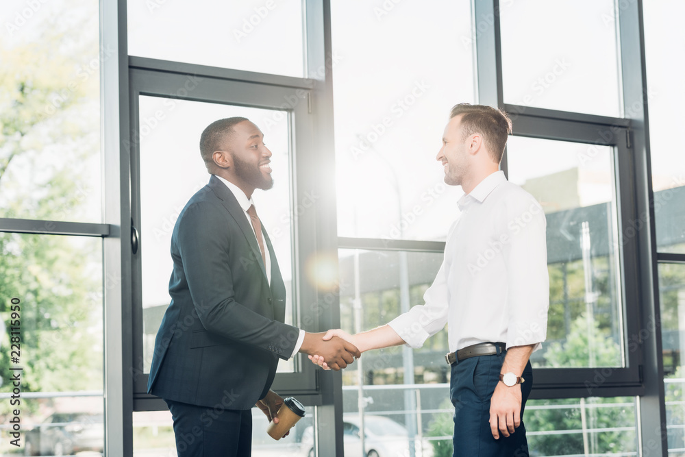 smiling multiracial business colleagues shaking hands in conference hall smiling multiracial business colleagues shaking hands in conference hall