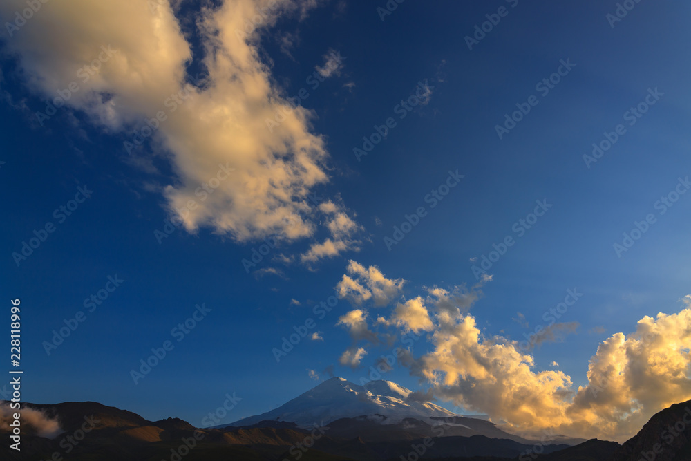 Mount Elbrus during sunset in the rays of the sun. Panoramic view of the mountain range in the North Caucasus in Russia.