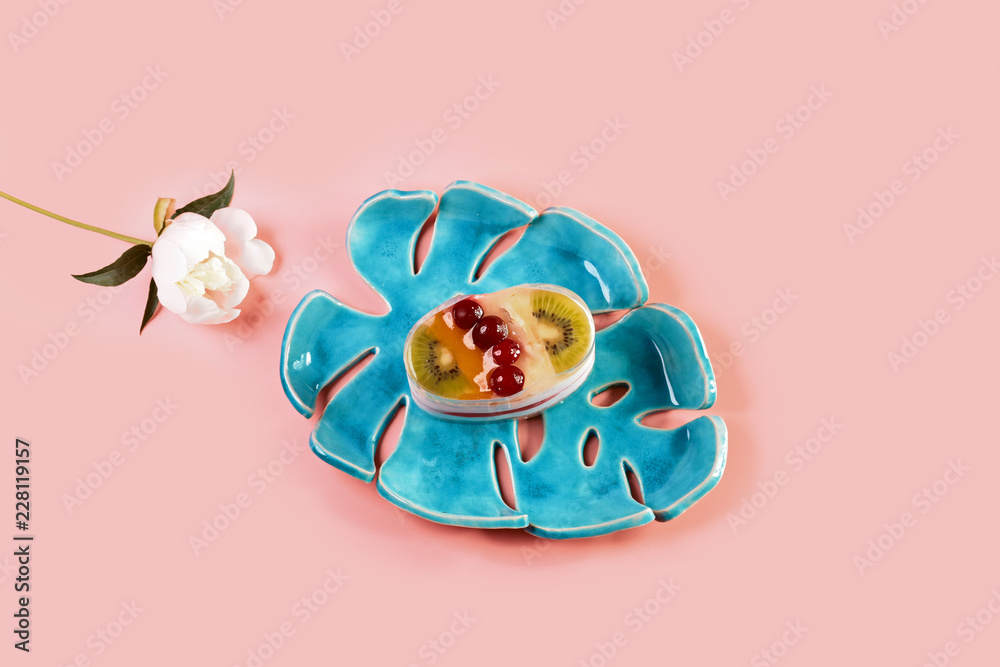 sweet cheesecake with fruit dessert on a pink pastel background. pottery on a blue plate with pions flowers. Flat lay. Copy space sweet cheesecake with fruit dessert on a pink pastel background. pottery on a blue plate with pions flowers. Flat lay. Copy space