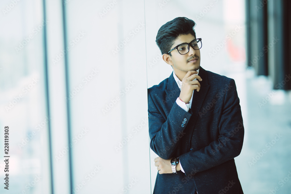 Young indian businessman thinking with hand on chin at office Young indian businessman thinking with hand on chin at office