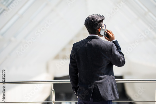 Rear view of businessman talking on phone in an office with panoramic view