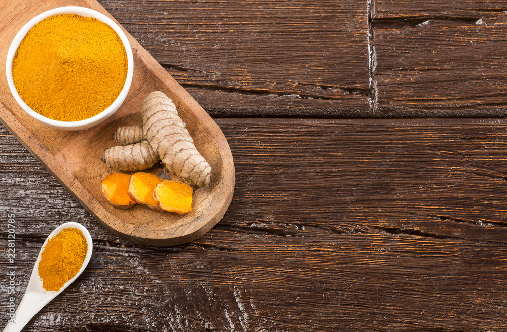 Turmeric roots and turmeric powder in white bowl - Curcuma longa
