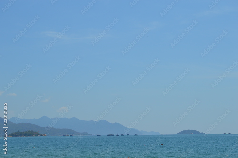 Far blue seascape with mountains on horizon. Vietnam Islands at the sun set. Blue sky with clouds