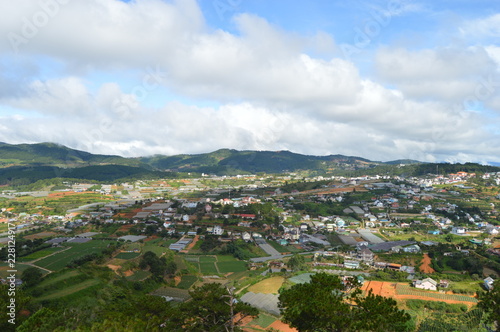 Green hill with the sky and clouds in the horizon. Trees and clouds in the background.City and houses in the backgound