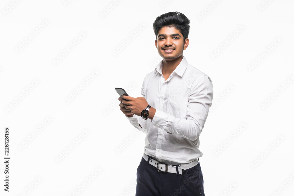 Young happy Indian man smiling while using mobile phone isolated on white background