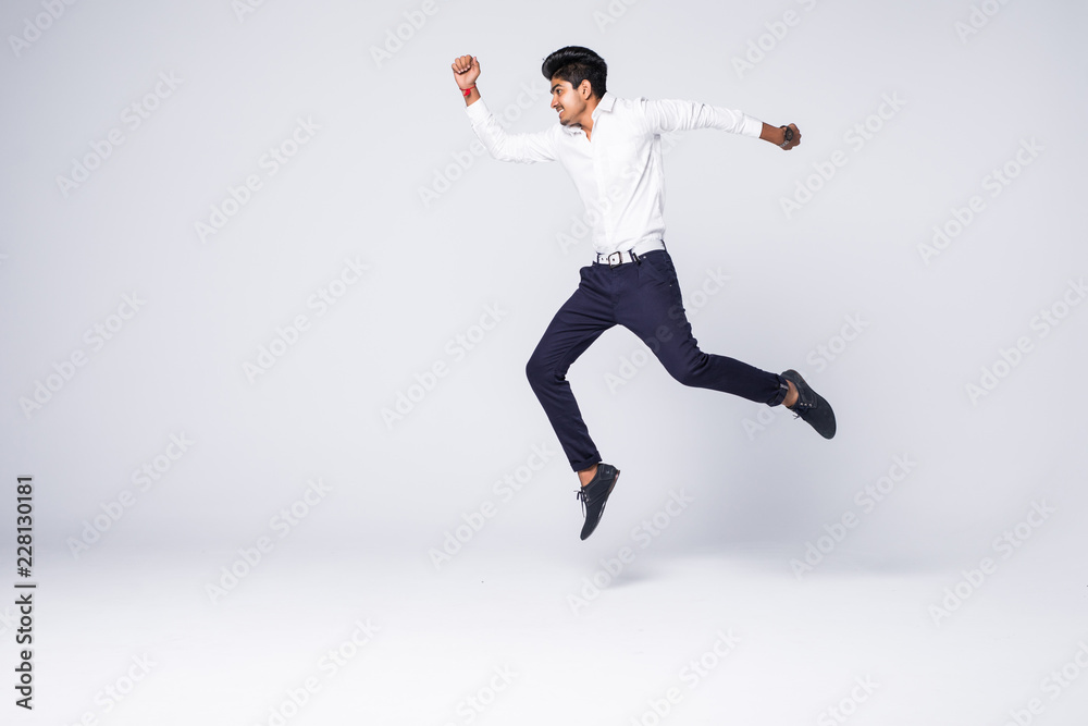 Full length of young indian man cheering and jumping isolated over white background