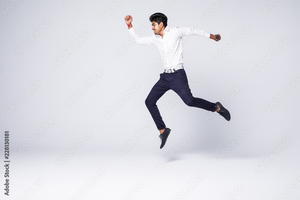 Full length of young indian man cheering and jumping isolated over white background Full length of young indian man cheering and jumping isolated over white background