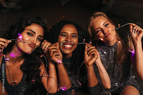 Happy friends making mustaches with christmas lights