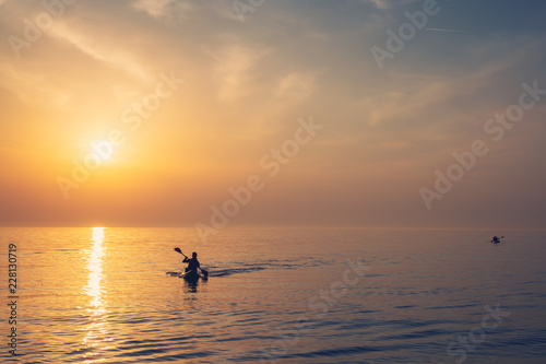 Beautiful Black sea sunrise in Odessa with silhouette of kayaking man and warm colors
